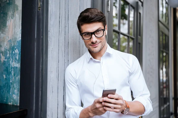 Hombre usando auriculares y escuchando música desde el teléfono celular —  Fotos de Stock