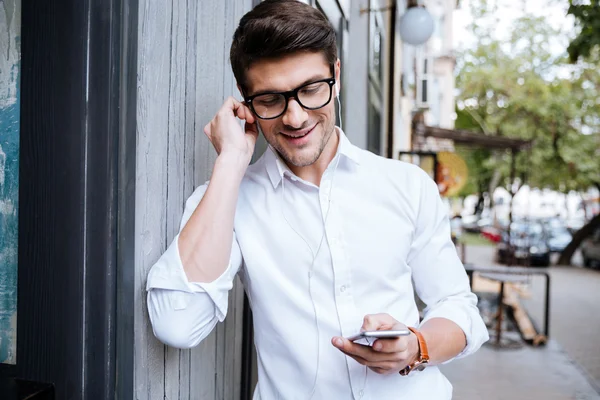 Glücklicher Mann, der auf der Straße Musik vom Handy hört — Stockfoto