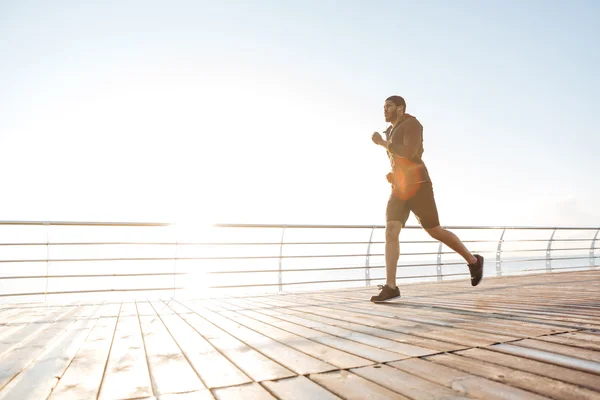 Hombre atractivo corriendo en terraza de madera — Foto de Stock