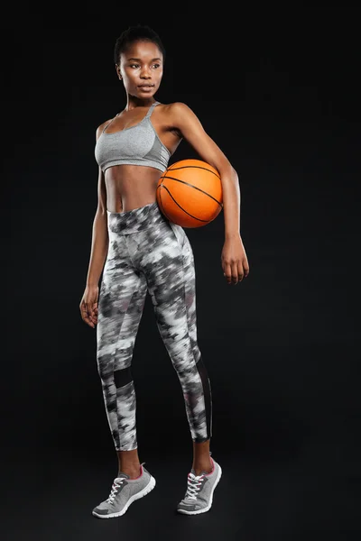 Retrato de cuerpo entero de una mujer deportiva sosteniendo pelota de baloncesto — Foto de Stock