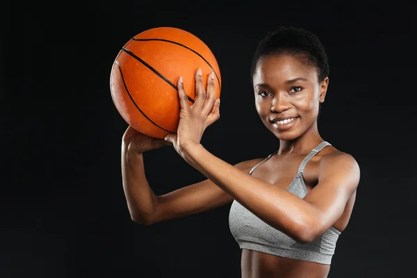 Portrét šťastné ženy v oblečení drží basketbal nad černou — Stock fotografie