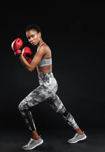Boxer femminile posa indossando guanti da boxe rossi e abbigliamento sportivo — Foto Stock
