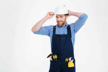 Portrait of happy bearded young builder in overall and helmet