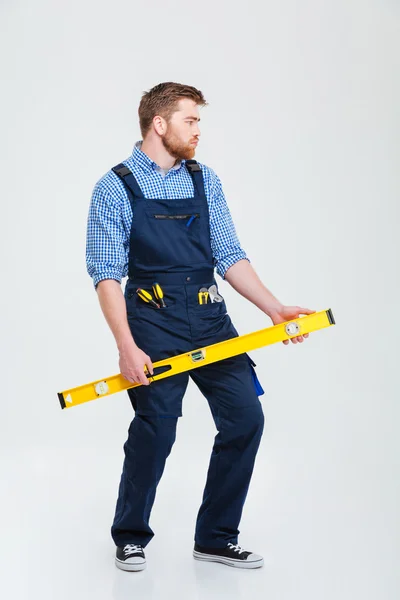 Funny male builder holding waterpas — Stock Photo, Image