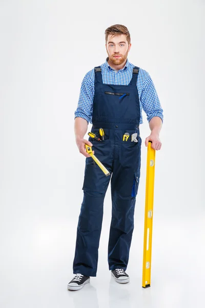 Construtor masculino barbudo segurando passagem d 'água e fita métrica — Fotografia de Stock