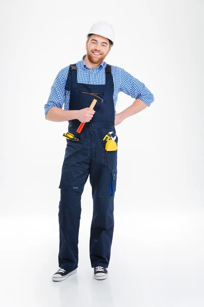 Щасливий молодий будівельник в шоломі стоїть і тримає молоток — стокове фото
