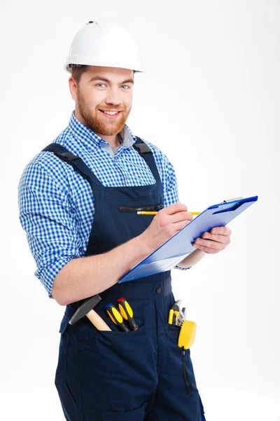 Glücklich selbstbewusste junge Bauarbeiter schreiben und verwenden Klemmbrett — Stockfoto