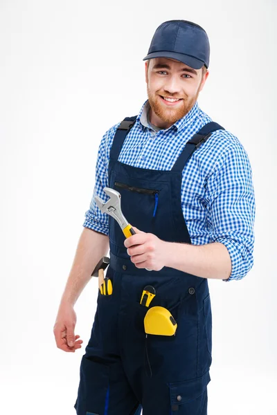 Fröhlicher bärtiger Reparateur steht und hält verstellbaren Schraubenschlüssel — Stockfoto