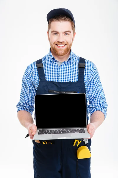 Щасливий будівельник в цілому і шапка тримає порожній екран ноутбук — стокове фото
