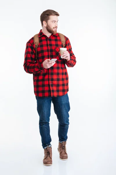 Homme heureux tenant tasse avec café et en utilisant un smartphone — Photo
