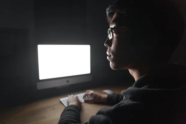 Jovem pensativo usando o computador em branco na sala escura — Fotografia de Stock