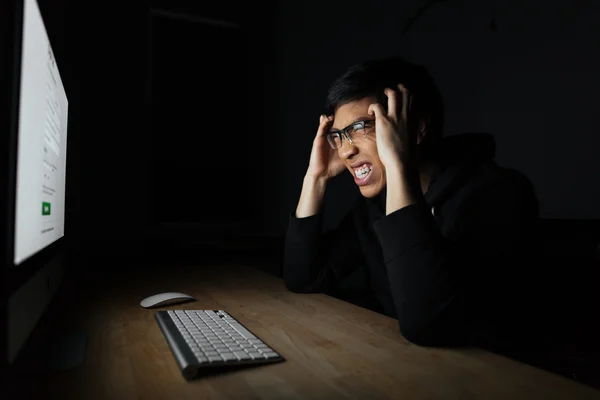 Uomo pazzo irritato che lavora con il computer in camera oscura — Foto Stock