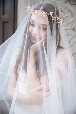 Güzel genç gelin peçe ile kaplı çelenk içinde gülümseyen