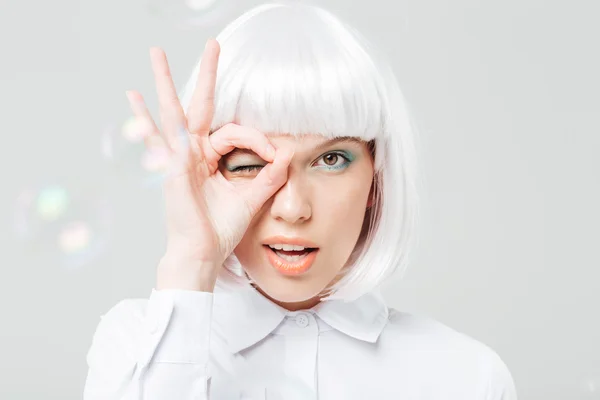 Playful charming young woman looking through her fingers — Stock Photo, Image