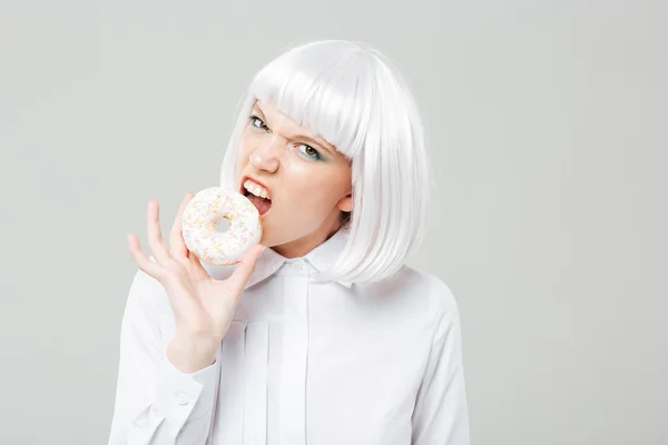 Zły dość młoda kobieta o blond włosach jedzenie świeże pączki — Zdjęcie stockowe