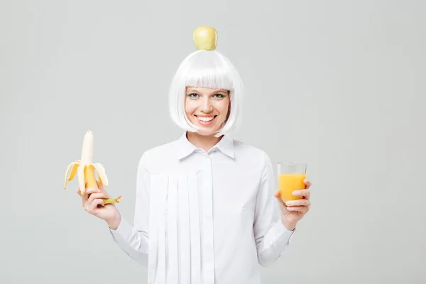 Cheerful young woman holding banana and glass of juice — Stock Photo, Image