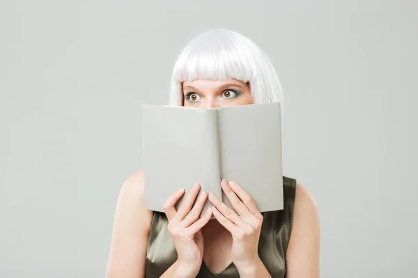 Félek, csinos, fiatal nő fedett arcát könyvet — Stock Fotó