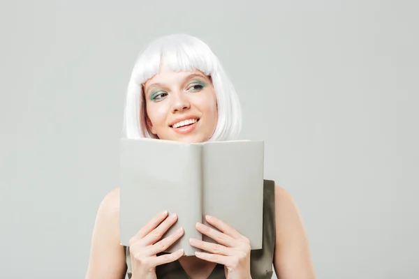 Glückliche Frau mit blonder Perücke, die lächelt und ein Buch liest — Stockfoto