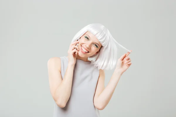 Glada lekfulla kvinna i blond peruk talar i mobiltelefon — Stockfoto