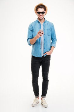 Akıllı telefon kullanarak şapka ve güneş gözlüğü neşeli kendinden emin genç adam