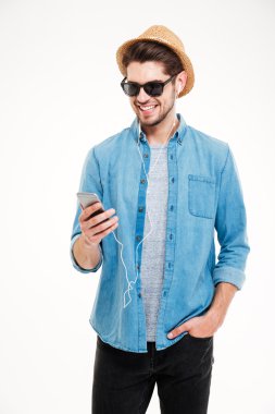 Neşeli genç adam ayakta ve akıllı telefon kullanarak