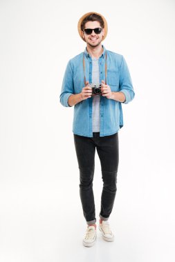 Neşeli genç adam ayakta ve eski vintage fotoğraf makinesi tutarak