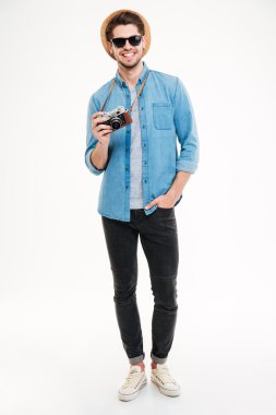 Eski fotoğraf makinesi kullanarak güneş gözlüğü ve şapka gülümseyen adam