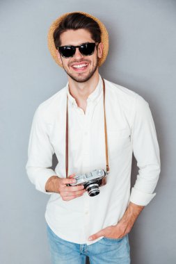 Şapka ve güneş gözlüğü ile eski vintage fotoğraf makinesi gülümseyen adam