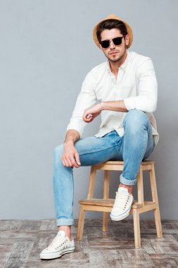 Kendine güvenen genç adam beyaz gömlek, şapka ve güneş gözlüğü