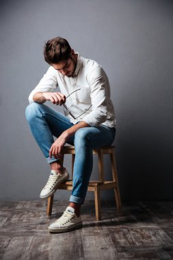 Üzgün üzgün genç adam oturmuş ve aşağı bakıyor