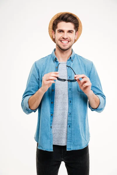 Joyeux homme confiant en chapeau et chemise bleue tenant des lunettes de soleil — Photo