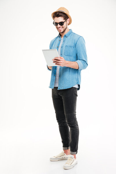 Full length of happy handsome young man using tablet
