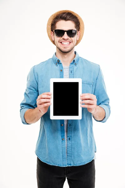 Hombre sonriente con sombrero y gafas de sol sosteniendo la tableta de pantalla en blanco — Foto de Stock