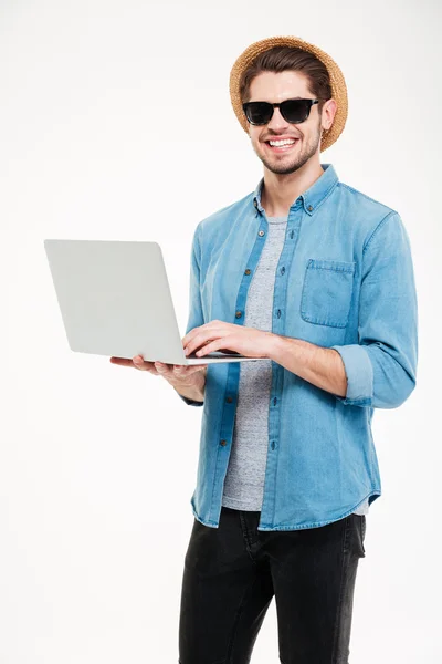 Šťastný pohledný mladý muž, který drží a používá přenosný počítač — Stock fotografie