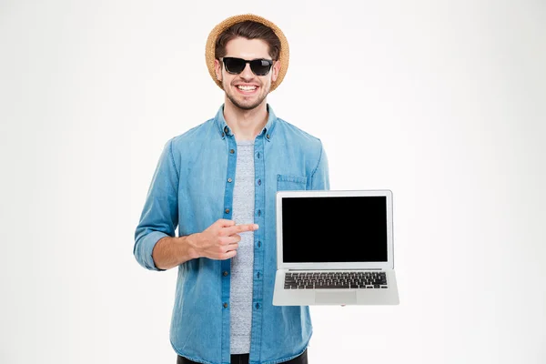 Feliz joven confiado apuntando en la computadora portátil de pantalla en blanco — Foto de Stock