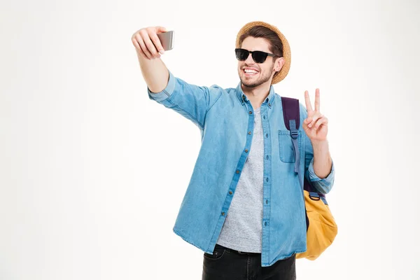 Hombre feliz con mochila haciendo selfie y mostrando señal de paz — Foto de Stock