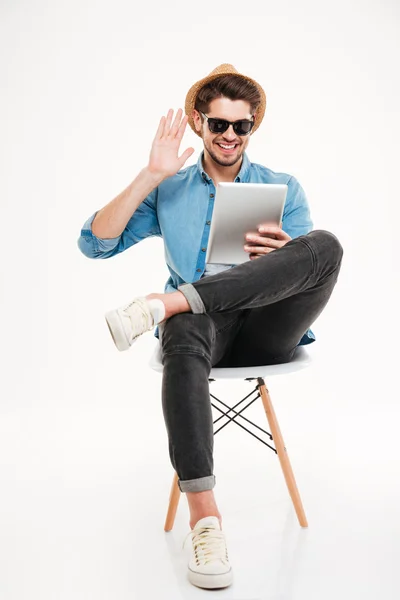 Homem sentado na cadeira e conversando usando tablet computador — Fotografia de Stock