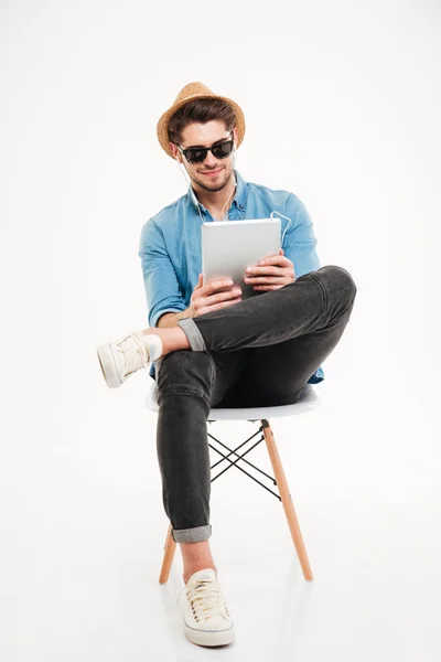 Hombre joven guapo usando tableta y sentado en la silla — Foto de Stock