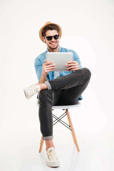 Schöner lächelnder Mann mit Tablet und auf dem Stuhl sitzend — Stockfoto