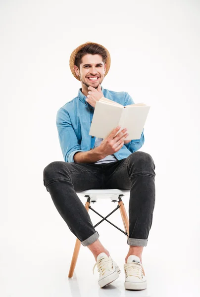Счастливый молодой человек сидит на стуле и читает книгу — стоковое фото