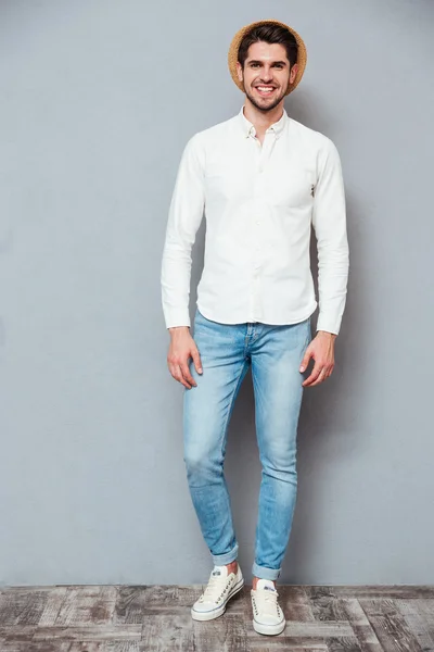 Bello sorridente giovane in camicia bianca, jeans e cappello — Foto Stock