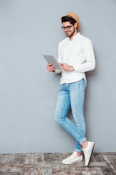 Full length portrait of a happy man using tablet computer