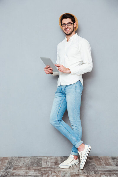 Full length portrait of a happy man using tablet computer