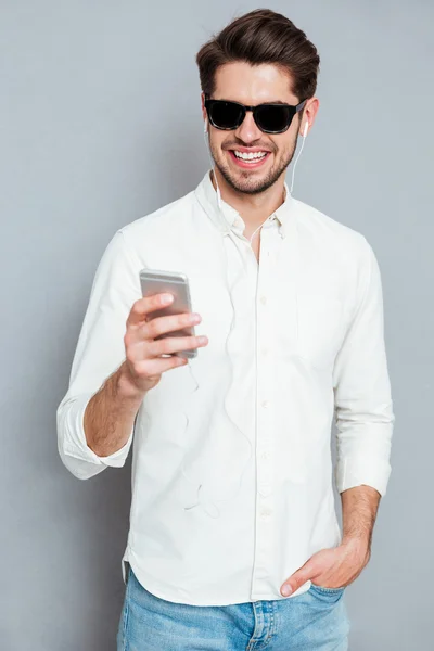 Portret van een casual Glimlachende man met smartphone — Stockfoto