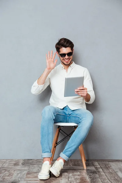 Hombre sonriente en gafas de sol usando tableta y teniendo videoconferencia — Foto de Stock