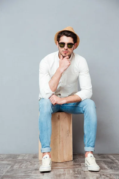 Töprengő fiatal férfi napszemüveg ül, és a gondolkodás — Stock Fotó