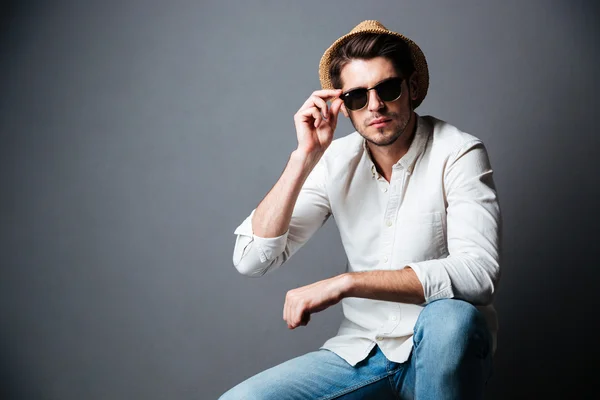 Porträtt av självsäker ung man i hatt och solglasögon — Stockfoto