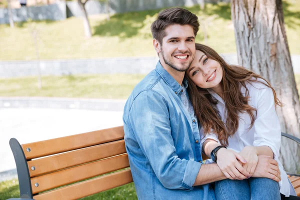 公園のベンチに座っている愛に幸せな若いカップル — ストック写真