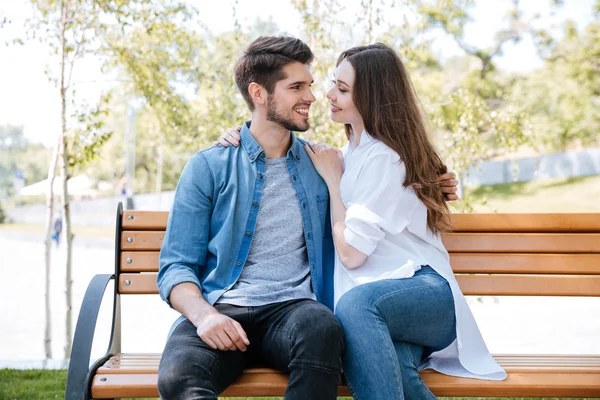 Feliz jovem casal apaixonado sentado em um banco de parque — Fotografia de Stock