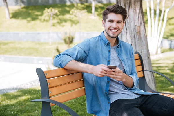 Portret szczęśliwy człowiek siedzi na ławce na zewnątrz — Zdjęcie stockowe